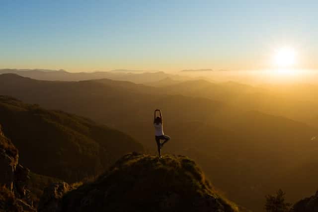 Woman stretching at mountain top during sunrise