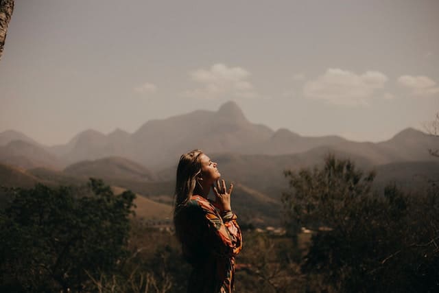 A girl facing upward with mountains in the background