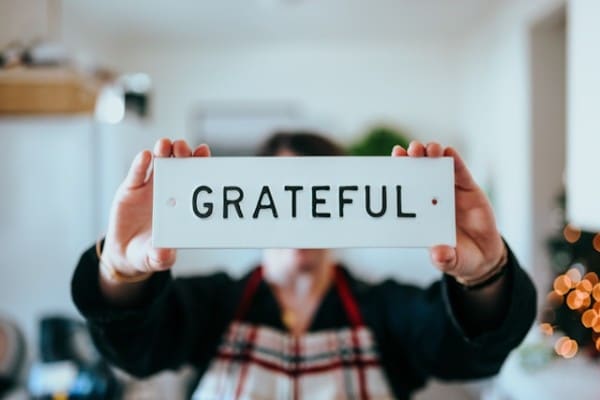 A person holding a board with "Grateful" written on it