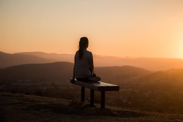Woman sitting on a bench looking mountains