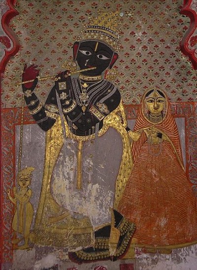 14th-century fresco of Radha (right) and Krishna (left, playing flute) in Udaipur, Rajasthan.